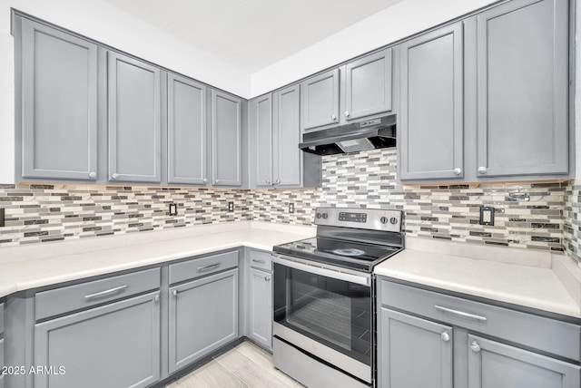 7207 W Alta Vista Rd, Laveen, AZ 85339 - kitchen featuring under cabinet range hood, stainless steel range with electric stovetop, gray cabinetry, light countertops, and decorative backsplash