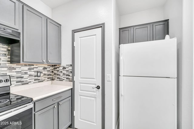 7207 W Alta Vista Rd, Laveen, AZ 85339 - kitchen featuring freestanding refrigerator, stainless steel electric range oven, gray cabinets, decorative backsplash, and light countertops