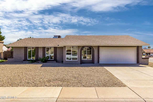 ranch-style home with concrete driveway, roof with shingles, and an attached garage