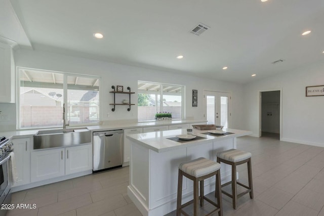 kitchen featuring a kitchen island, a sink, visible vents, stainless steel dishwasher, and a kitchen bar