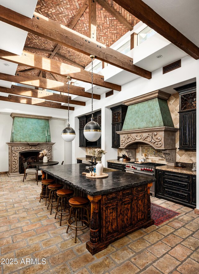 kitchen featuring designer range, premium range hood, beam ceiling, a large island, and backsplash