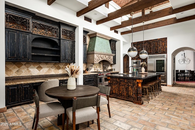 dining space featuring arched walkways, a chandelier, beamed ceiling, visible vents, and a high ceiling