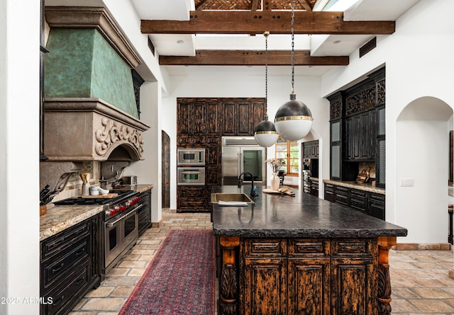 kitchen featuring arched walkways, a high ceiling, a sink, and built in appliances