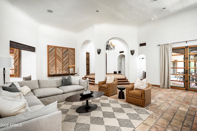 living room with recessed lighting, arched walkways, stone tile flooring, baseboards, and a high ceiling