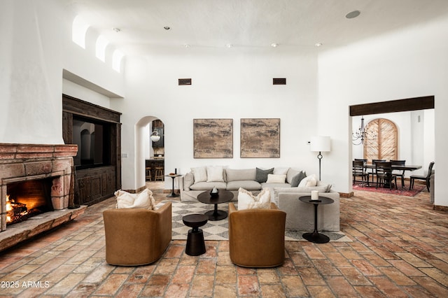 living area featuring a high ceiling, arched walkways, brick floor, and a fireplace