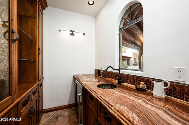 bathroom with vanity, stone finish floor, decorative backsplash, and baseboards