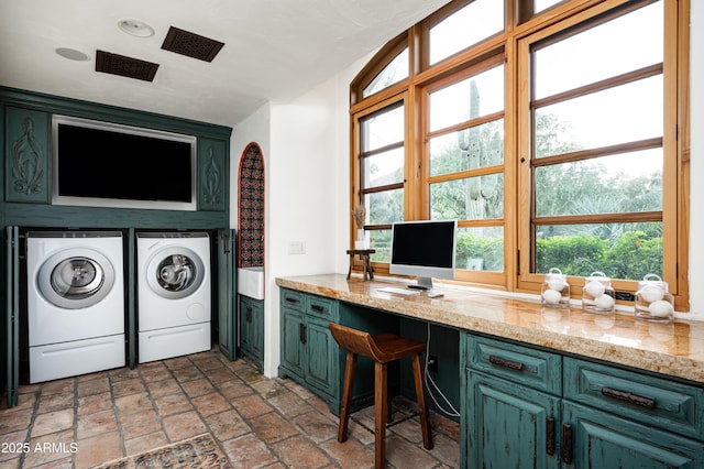 laundry room featuring stone tile flooring, separate washer and dryer, and cabinet space