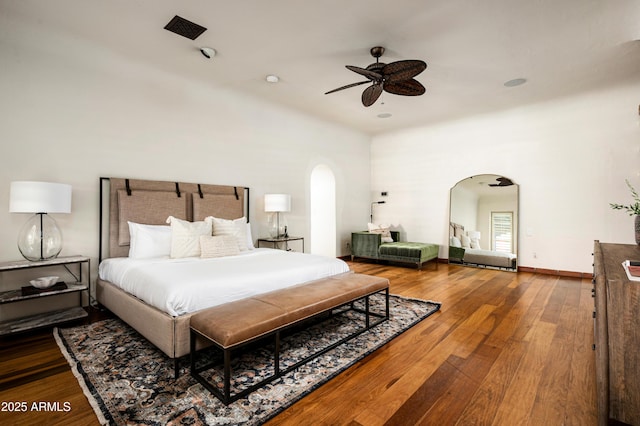 bedroom featuring arched walkways, ceiling fan, a high ceiling, and wood finished floors