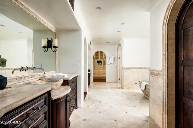 bathroom with a wainscoted wall, tile walls, recessed lighting, and vanity
