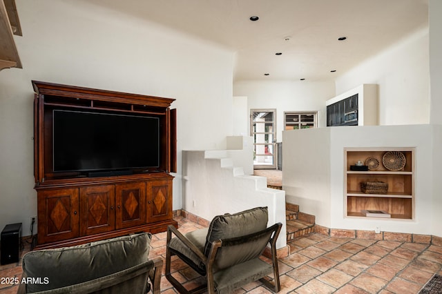 living room featuring stone tile flooring, recessed lighting, and built in shelves