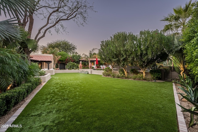 yard at dusk with a gazebo and a fenced backyard