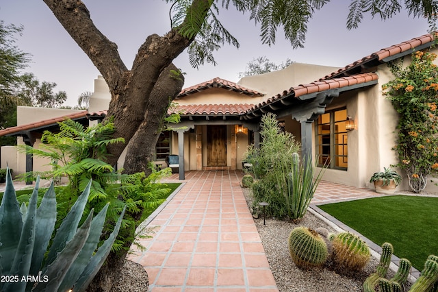 exterior space with a tile roof, a lawn, and stucco siding