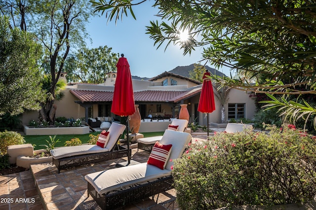 back of property featuring a tile roof, a patio area, an outdoor living space, a chimney, and stucco siding