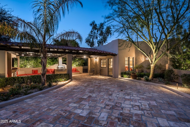 mediterranean / spanish house featuring stucco siding, exterior kitchen, a tiled roof, and a patio area