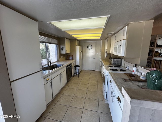 kitchen featuring sink, white cabinetry, light tile patterned floors, white appliances, and a textured ceiling