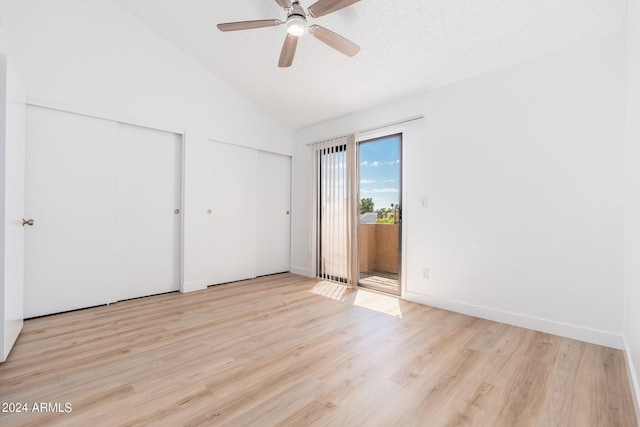 unfurnished bedroom with access to exterior, vaulted ceiling, a textured ceiling, light wood-style floors, and two closets