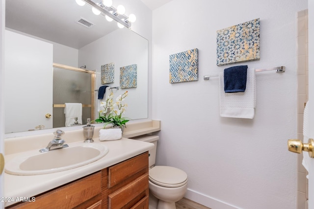 bathroom featuring toilet, a shower with door, visible vents, and vanity