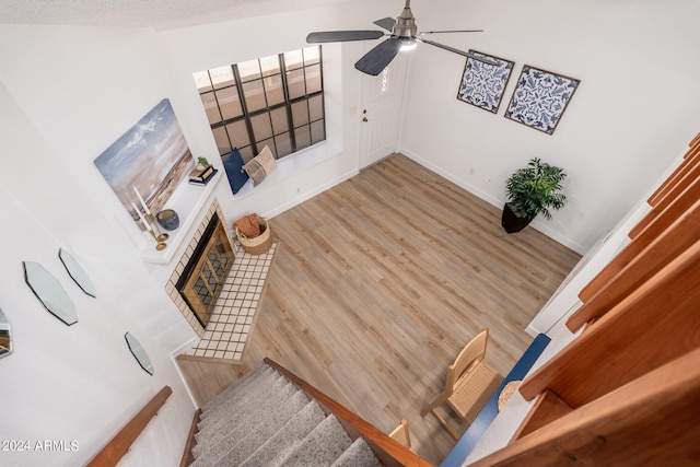 interior space featuring a tile fireplace, wood finished floors, a ceiling fan, and baseboards