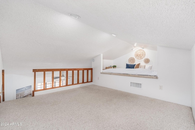 additional living space featuring carpet floors, lofted ceiling, visible vents, and a textured ceiling