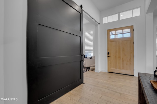 entryway with a barn door and light hardwood / wood-style flooring