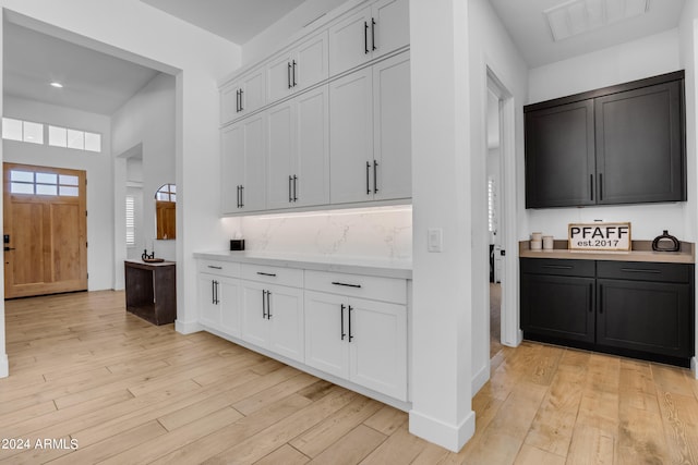 kitchen with white cabinets, light hardwood / wood-style floors, and tasteful backsplash