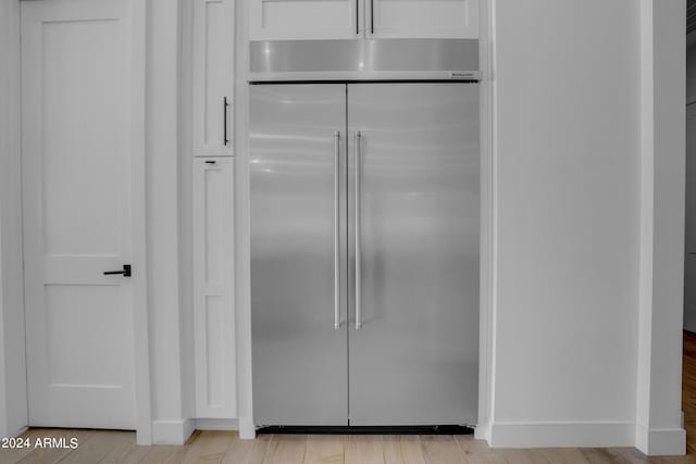 kitchen with light hardwood / wood-style flooring, stainless steel built in fridge, and white cabinets