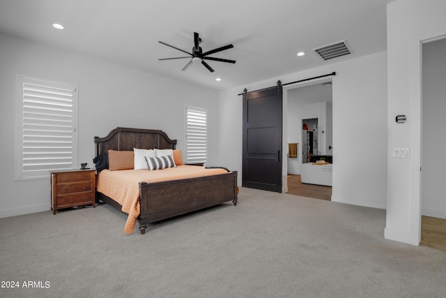 carpeted bedroom with ceiling fan and a barn door