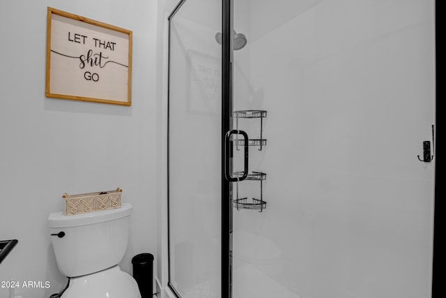 bathroom featuring a shower with shower door and toilet