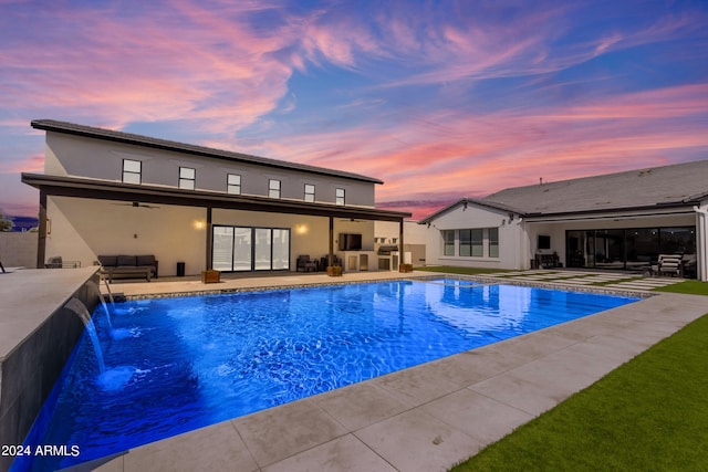 pool at dusk featuring an outdoor living space, pool water feature, and a patio area