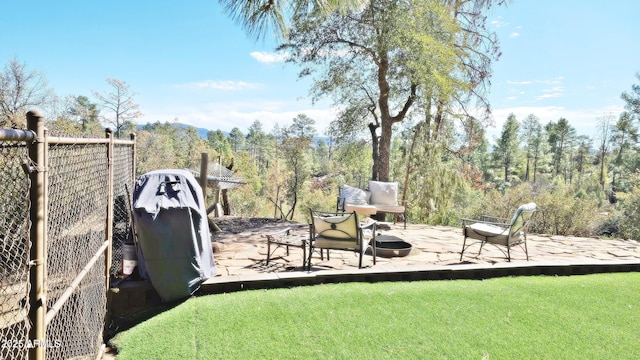 view of yard featuring a fire pit, a patio, and a wooded view