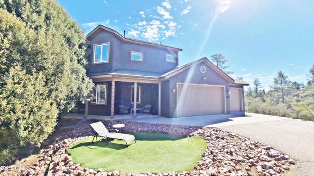 view of front of home with driveway, an attached garage, a front yard, and stucco siding