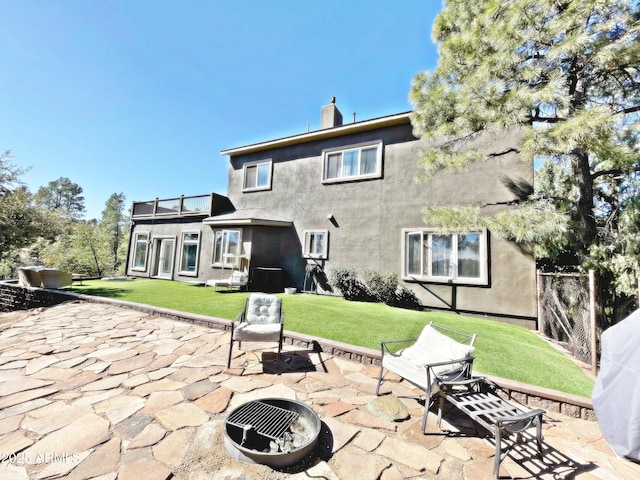 back of house featuring a patio area, a yard, a fire pit, and stucco siding