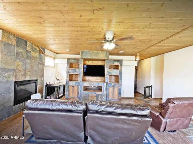 living room with wood ceiling, a fireplace, a ceiling fan, and wood finished floors