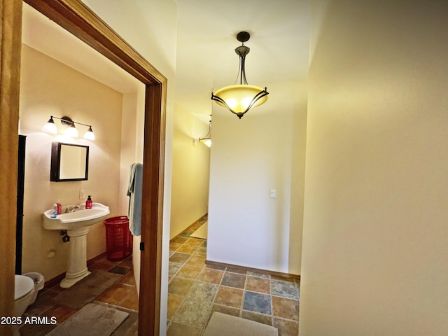 half bathroom featuring stone finish floor and baseboards