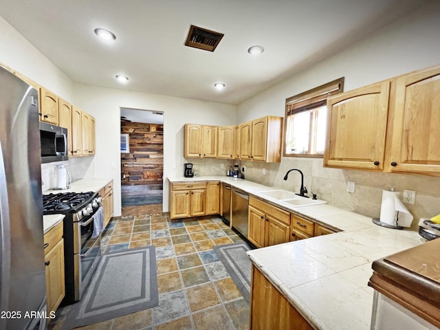 kitchen featuring visible vents, decorative backsplash, light brown cabinetry, appliances with stainless steel finishes, and a sink