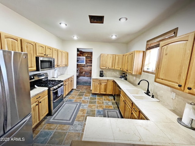 kitchen featuring tasteful backsplash, visible vents, appliances with stainless steel finishes, stone finish floor, and a sink