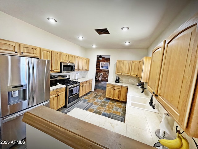 kitchen featuring appliances with stainless steel finishes, light brown cabinets, a sink, and visible vents