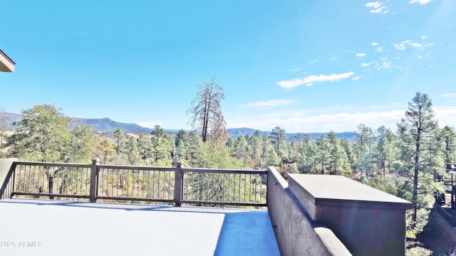 view of patio with a forest view, a balcony, and a mountain view