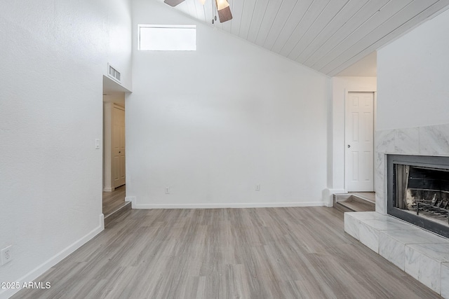 unfurnished living room featuring ceiling fan, wood finished floors, a tile fireplace, baseboards, and high vaulted ceiling