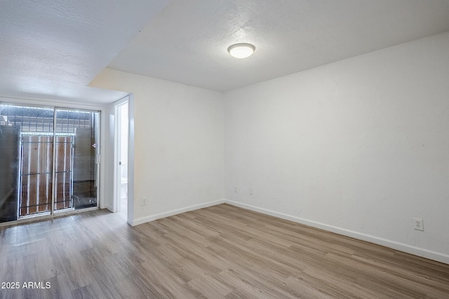 spare room featuring wood finished floors, baseboards, and a textured ceiling