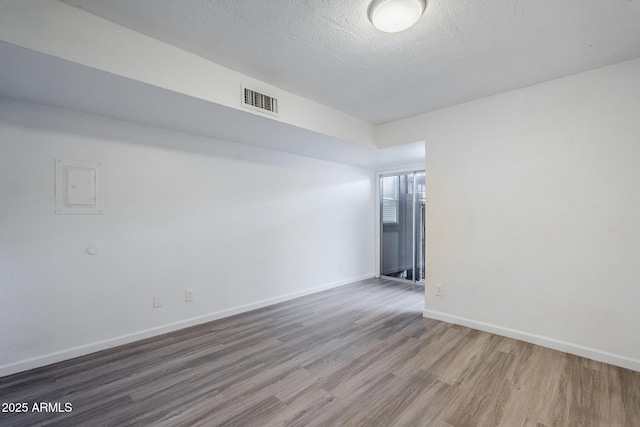 spare room featuring wood finished floors, baseboards, and a textured ceiling