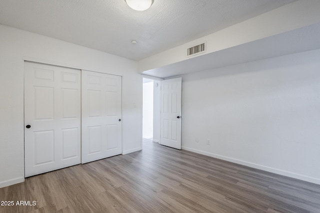unfurnished bedroom featuring wood finished floors, baseboards, and a closet