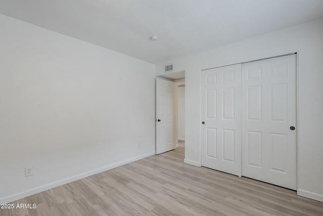 unfurnished bedroom with light wood finished floors, baseboards, and a closet