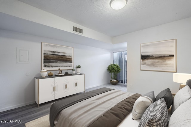 bedroom featuring wood finished floors, baseboards, and a textured ceiling