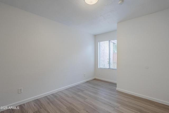 spare room featuring wood finished floors, baseboards, and a smoke detector