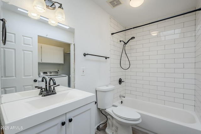 bathroom featuring washing machine and dryer, toilet, vanity, and shower / tub combination
