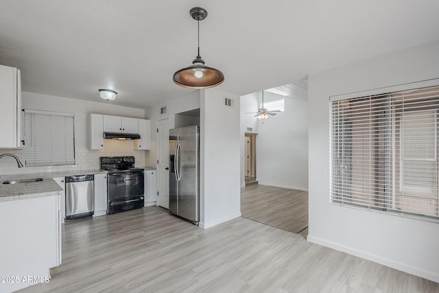kitchen featuring appliances with stainless steel finishes, under cabinet range hood, light wood-style floors, ceiling fan, and a sink