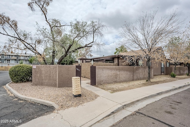 view of side of home with a fenced front yard and stucco siding