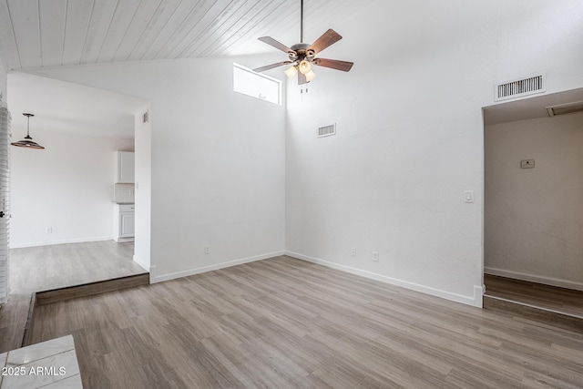 spare room featuring ceiling fan, vaulted ceiling, light wood finished floors, and baseboards