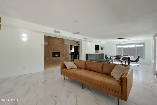living area featuring a large fireplace, marble finish floor, and visible vents